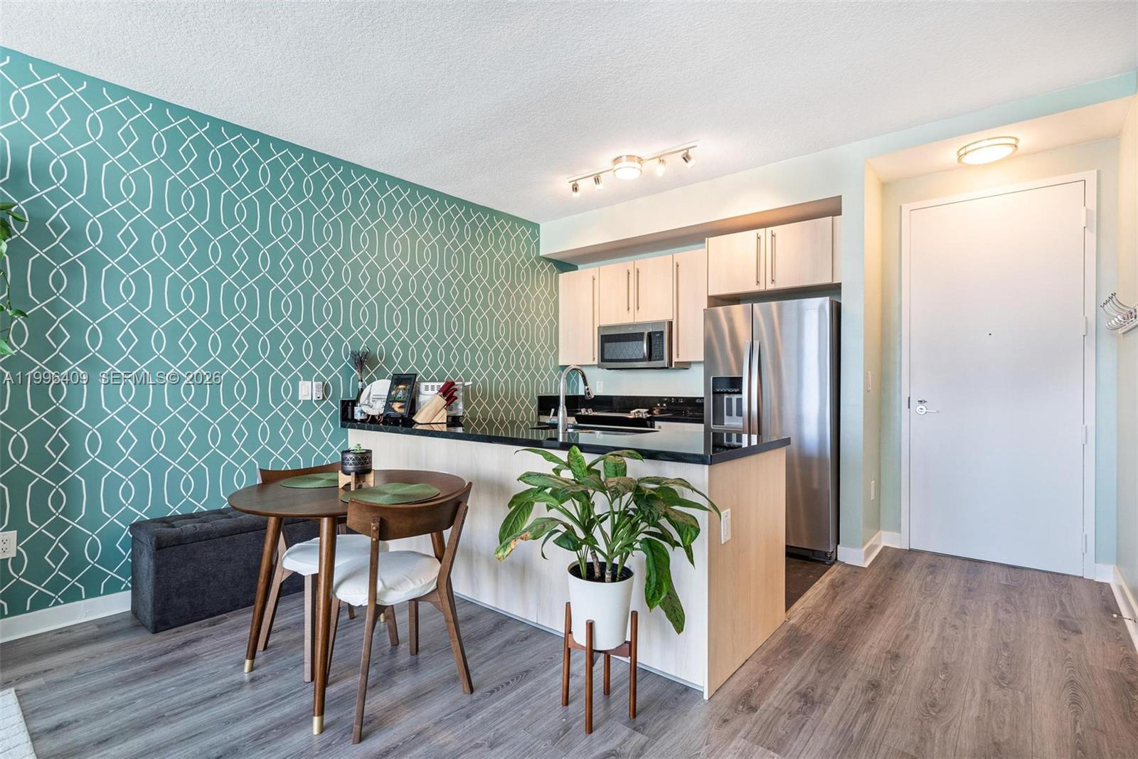 A kitchen with light wood cabinets, stainless steel appliances, and a teal patterned accent wall — 1111 SW 1st Ave, Miami FL 33130, MIAMI, FL