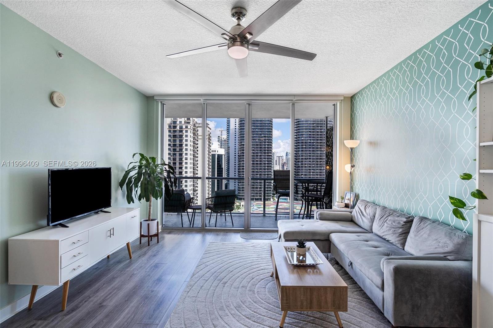 A living room features a gray sectional sofa, a television console, and a balcony view — 1111 SW 1st Ave, Miami FL 33130, MIAMI, FL