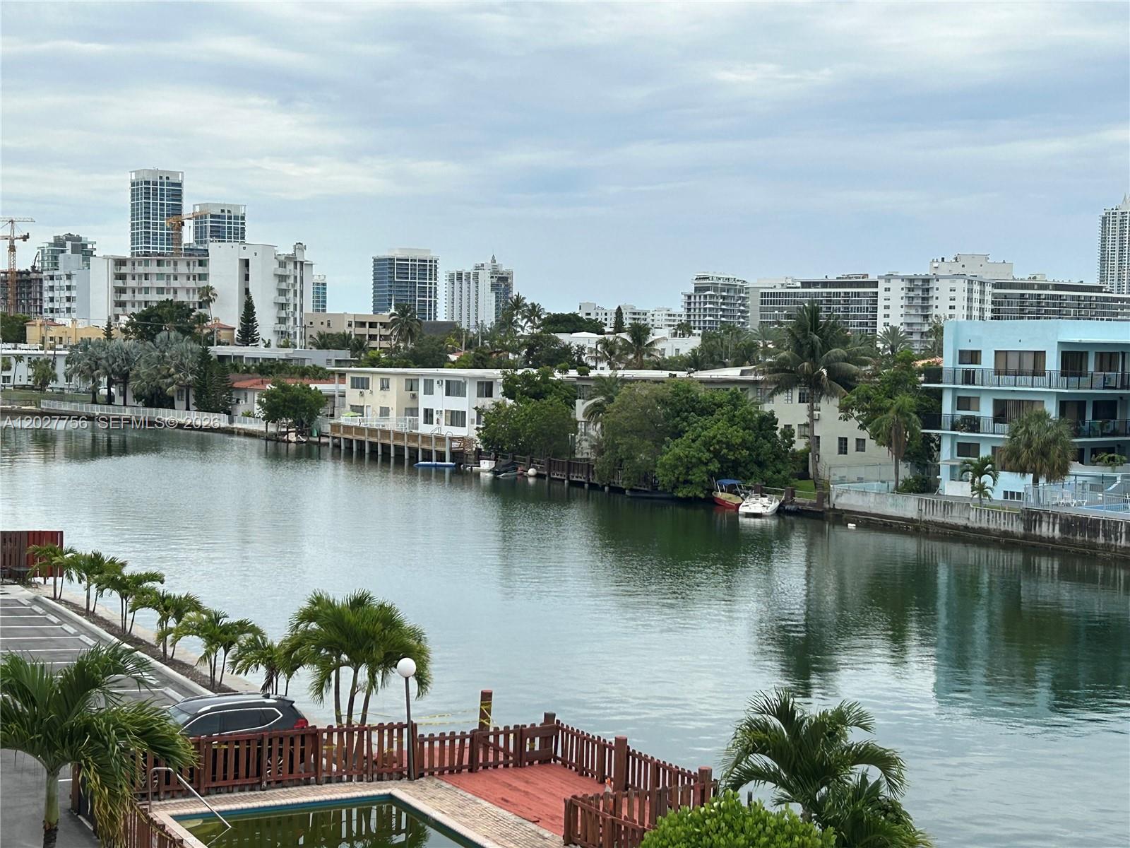 An elevated view of a canal with surrounding apartment buildings, palm trees, and a pool — 110 S Shore Dr # 4E, Miami Beach FL 33141, MIAMI BEACH, FL