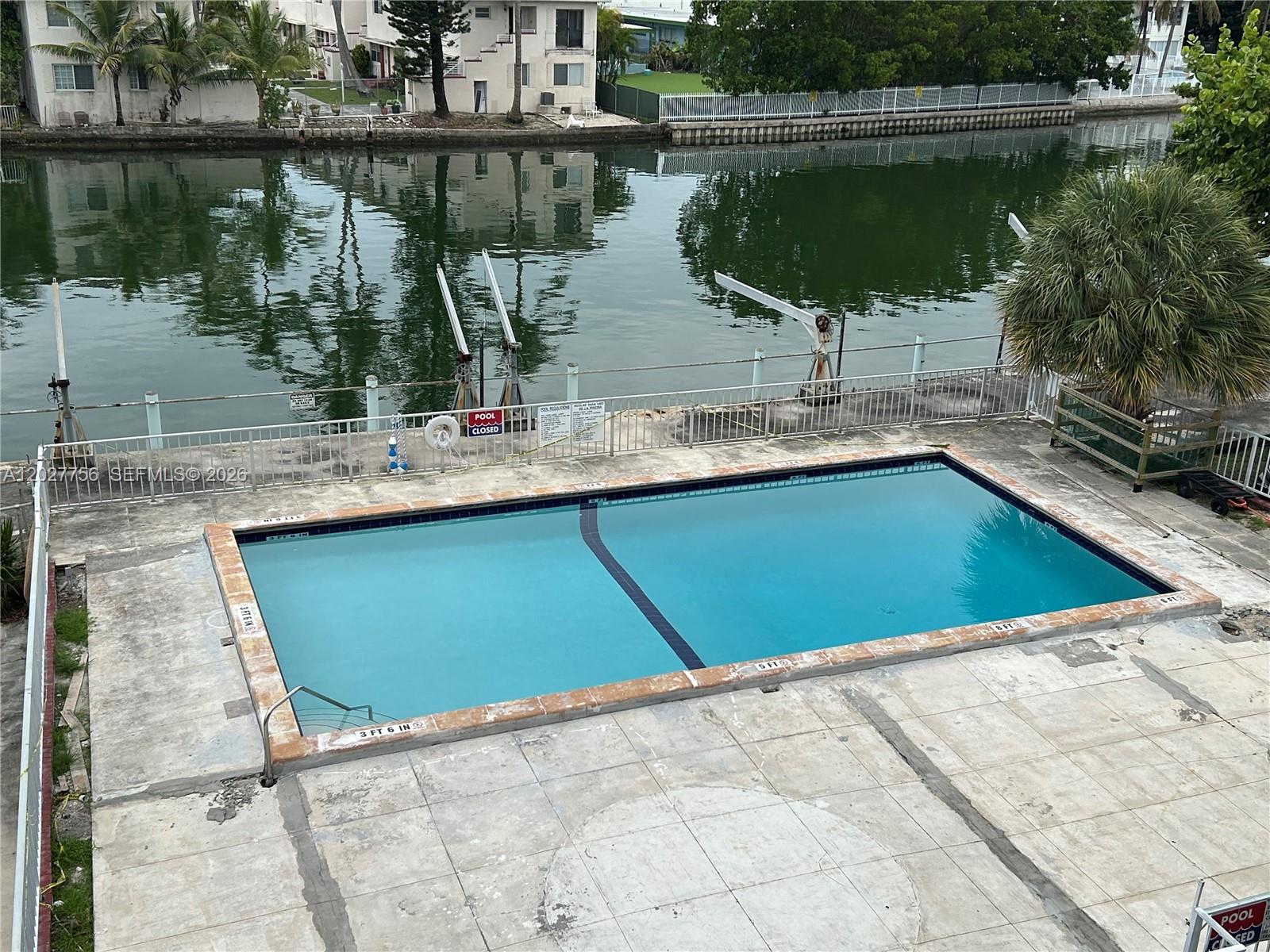 An outdoor rectangular swimming pool sits on a concrete deck beside a canal — 110 S Shore Dr # 4E, Miami Beach FL 33141, MIAMI BEACH, FL