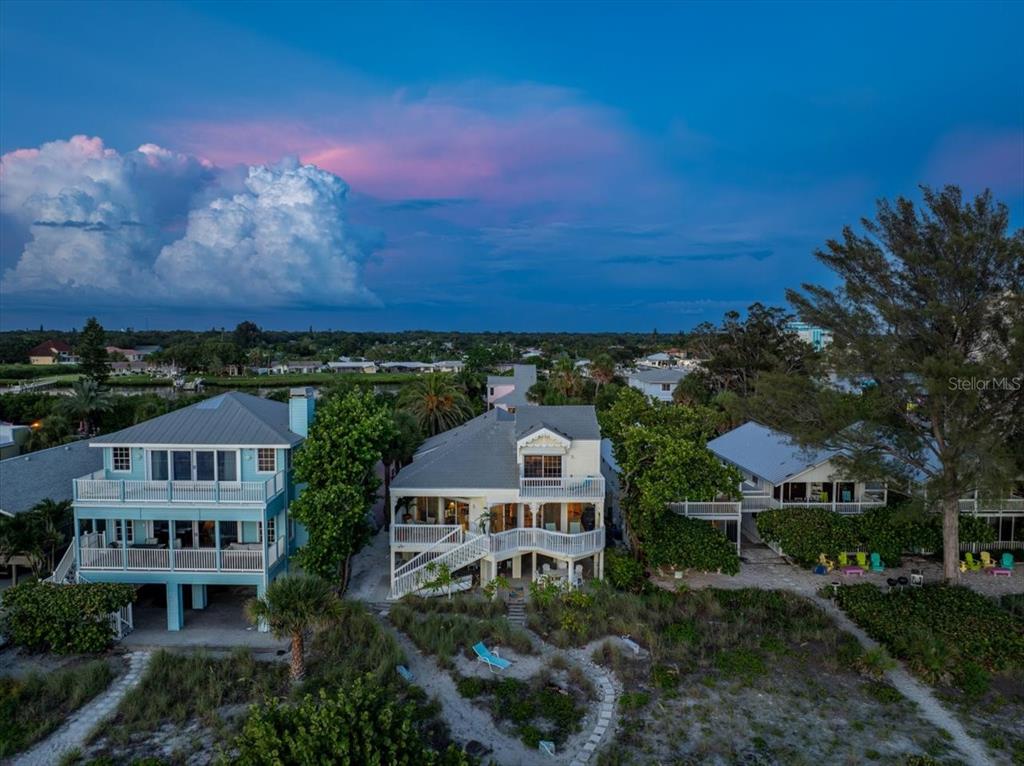 An aerial view of two elevated beach houses with balconies overlooking a sandy coastal landscape — 20052 GULF BOULEVARD, INDIAN SHORES, FL