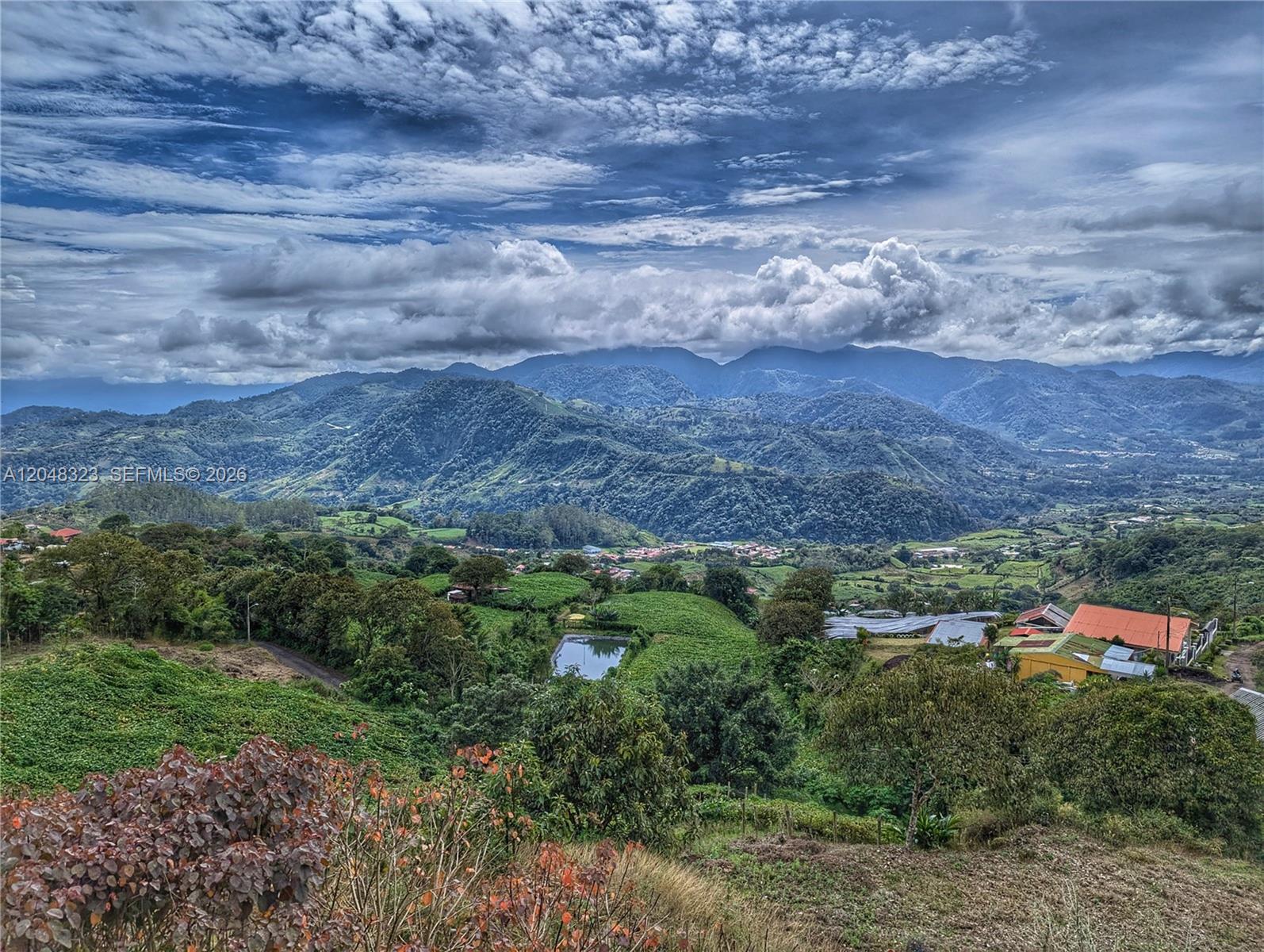 A high-angle view shows a lush green valley with a small pond and distant mountains — 6 Cervantes Cartago Costa Rica, CR 00, CR