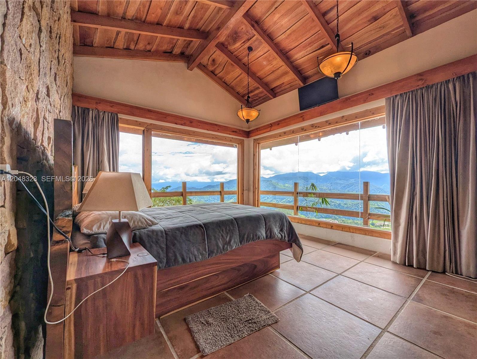 A bedroom with a wooden vaulted ceiling, tile floors, and large windows overlooking mountain views — 6 Cervantes Cartago Costa Rica, CR 00, CR