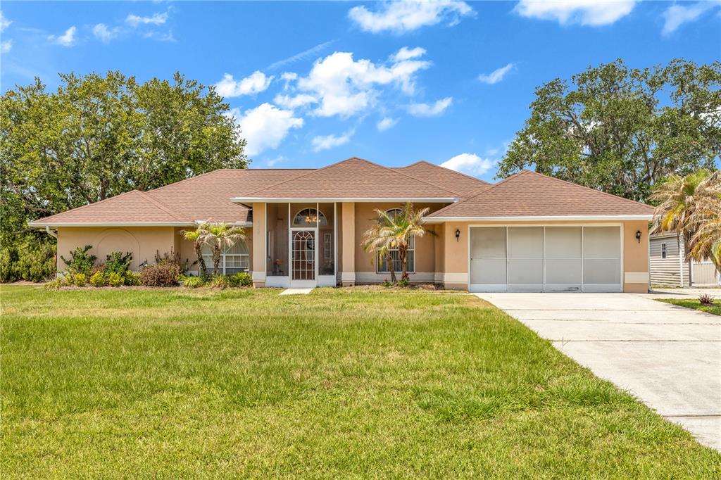 A single-story house with a tan stucco exterior, brown shingled roof, and a screened entryway — 2800 WOODSMERE COURT, KISSIMMEE, FL