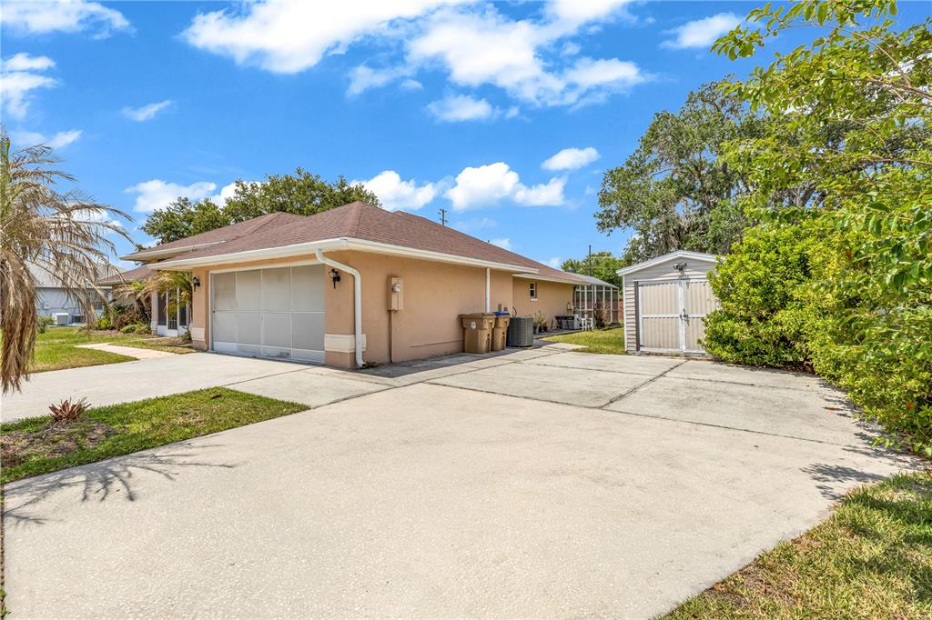 A tan house with a brown roof, a concrete driveway, and a small detached shed — 2800 WOODSMERE COURT, KISSIMMEE, FL