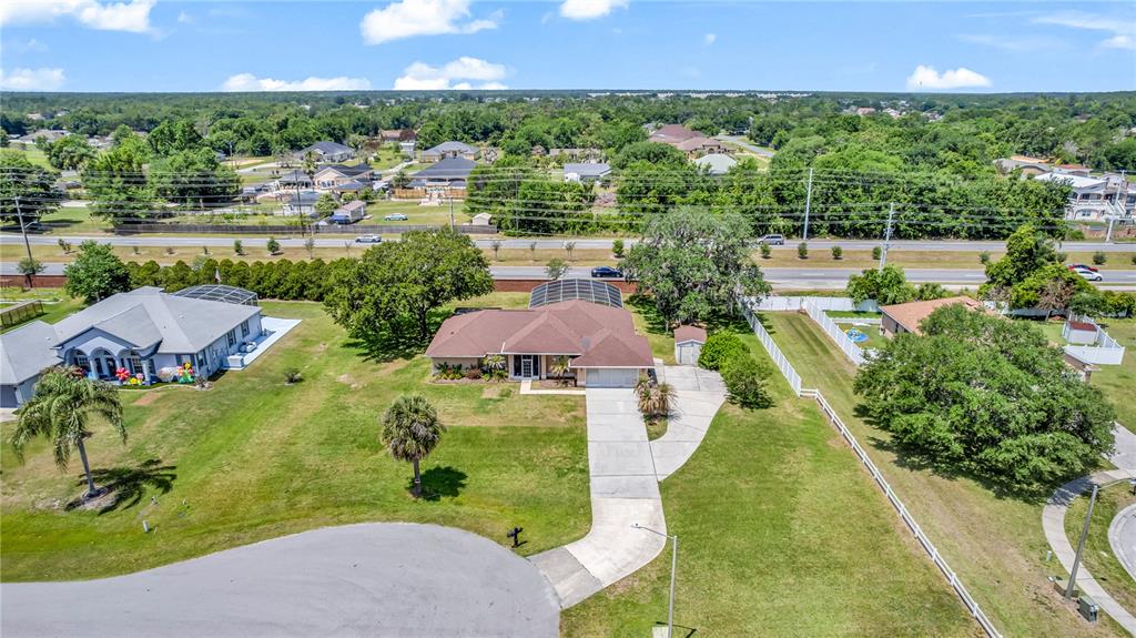 An aerial view shows a single-story house with a pool enclosure and a long driveway — 2800 WOODSMERE COURT, KISSIMMEE, FL