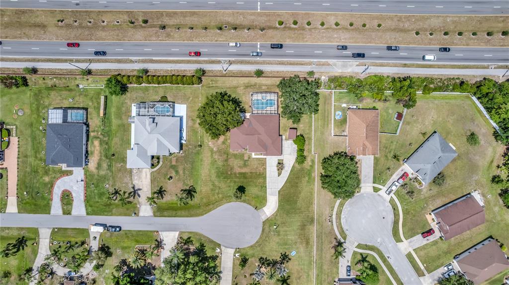 This aerial view shows several suburban houses with swimming pools and driveways near a highway — 2800 WOODSMERE COURT, KISSIMMEE, FL