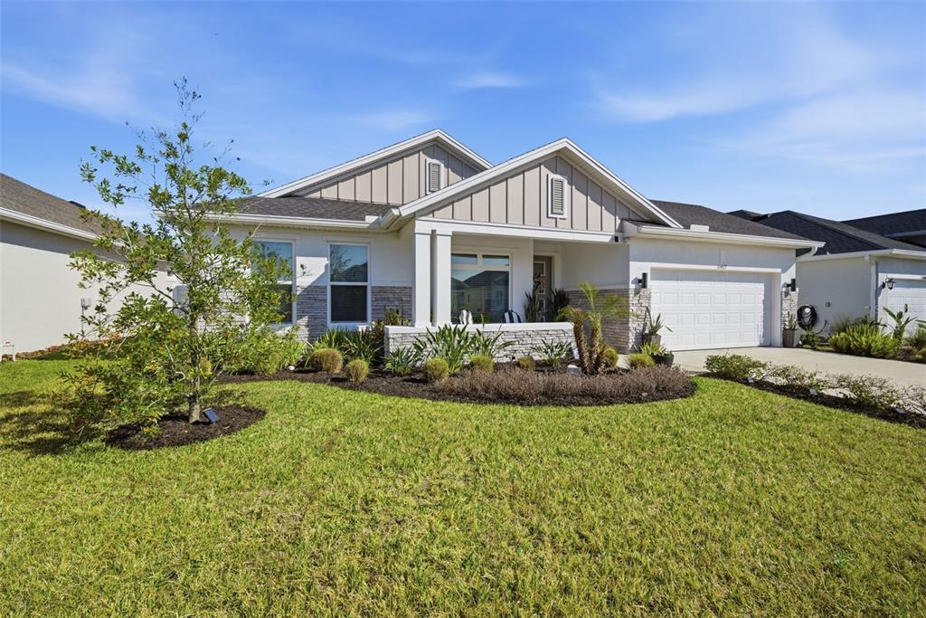 A single-story house features a stone-accented facade, vertical siding, a front porch, and a garage — 31477 WESTBURY ESTATES AVENUE, WESLEY CHAPEL, FL