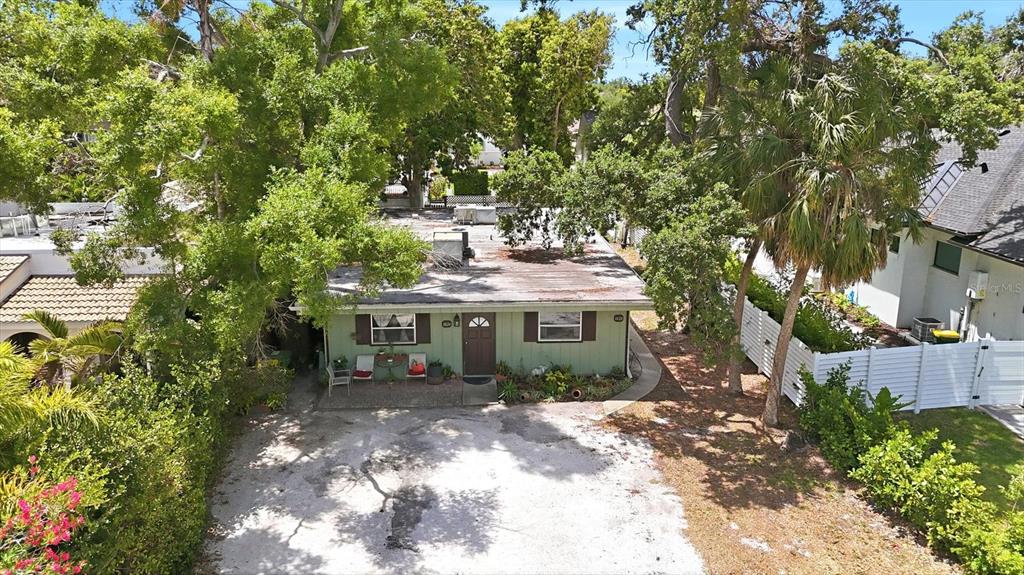 An aerial view shows a single-story green house with a flat roof and gravel driveway — 1824 WEBBER STREET, SARASOTA, FL