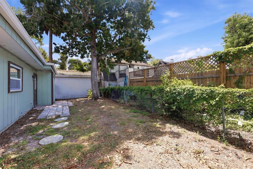 A side yard features a light green house, a stone path, and a wooden fence — 1824 WEBBER STREET, SARASOTA, FL
