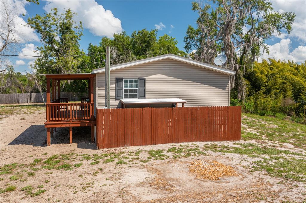 A tan mobile home with a wooden deck and a brown privacy fence — 991 BAY COURT, FROSTPROOF, FL
