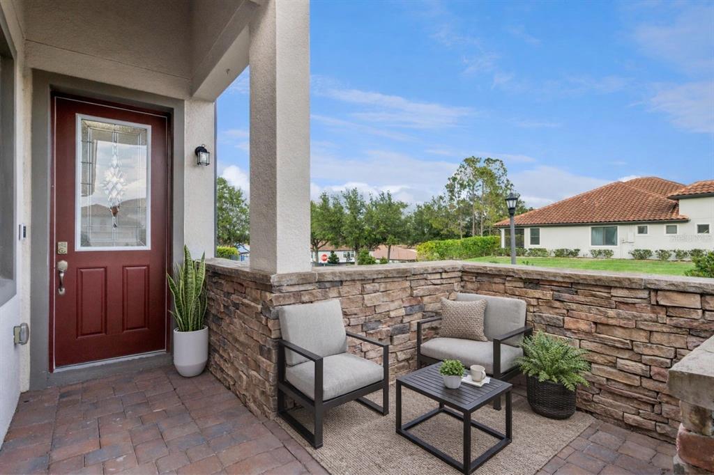 A covered front porch features stone walls, two chairs, a small table, and a door — 4168 SOLAMOR STREET, LAKELAND, FL