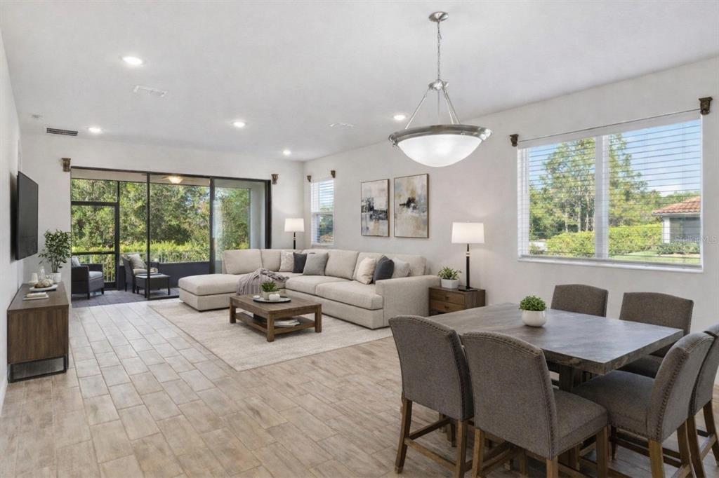 An open-concept living and dining area with tile floors, a sectional sofa, and sliding doors — 4168 SOLAMOR STREET, LAKELAND, FL
