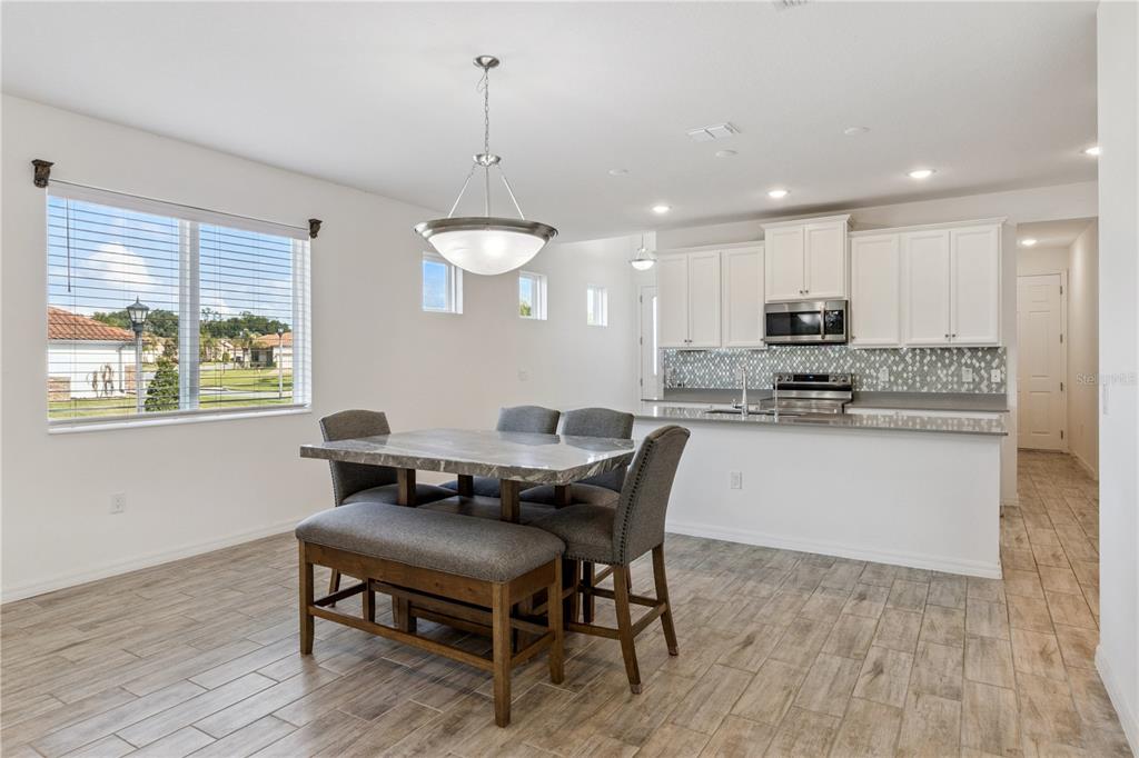 A dining area with a marble-topped table and a kitchen with white cabinets and tile — 4168 SOLAMOR STREET, LAKELAND, FL
