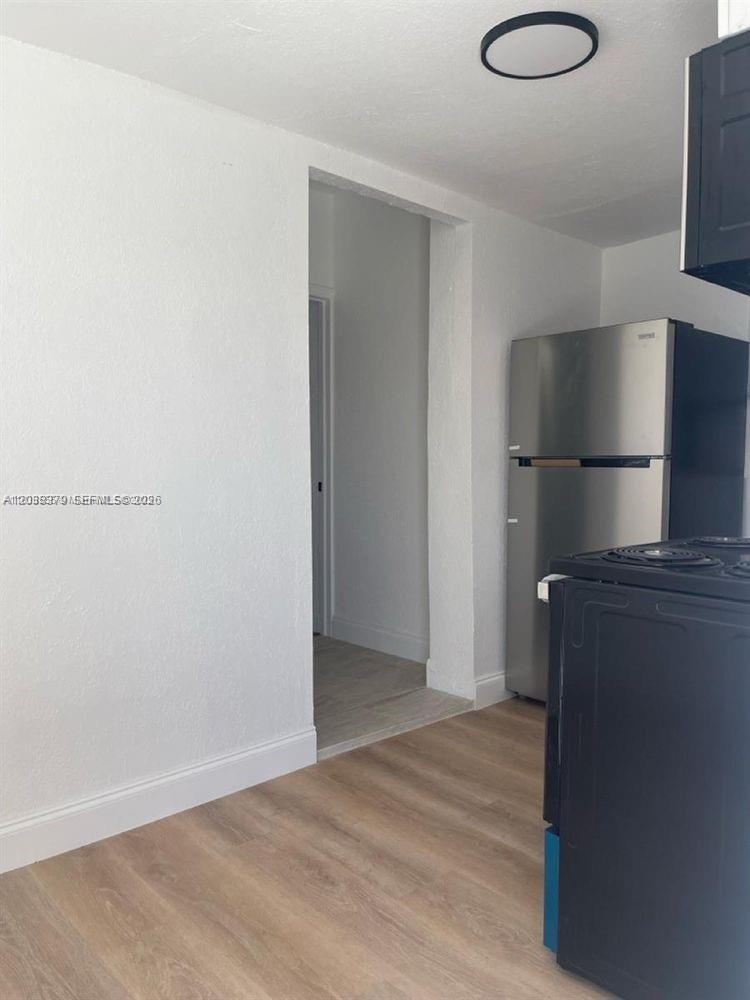 A kitchen features light wood-look flooring, white walls, a stainless steel refrigerator, and a stove — 219 SW 21st Ave # 3, Miami FL 33135, MIAMI, FL