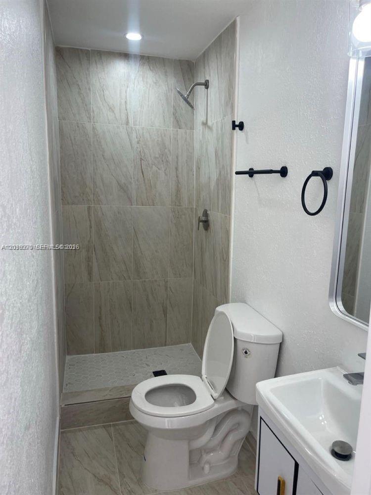 A small bathroom features a tiled walk-in shower, a white toilet, and a vanity sink — 219 SW 21st Ave # 3, Miami FL 33135, MIAMI, FL