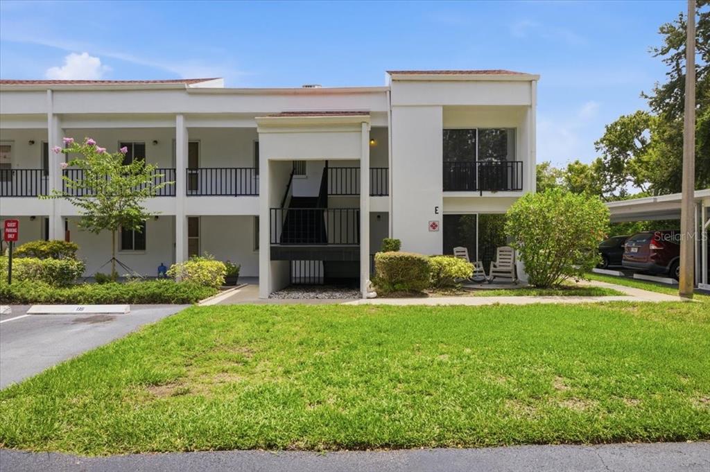 A two-story white apartment building features a central staircase and a ground-level patio area — 2060 MARILYN STREET UNIT 236, CLEARWATER, FL