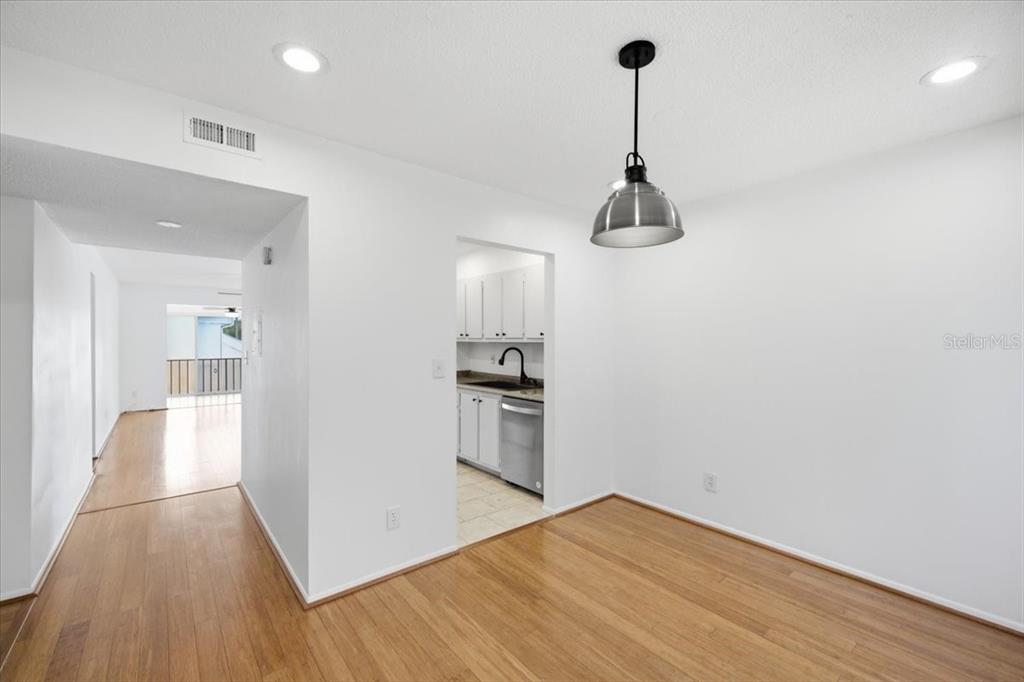 A dining area with wood flooring and a pendant light leads to a kitchen — 2060 MARILYN STREET UNIT 236, CLEARWATER, FL