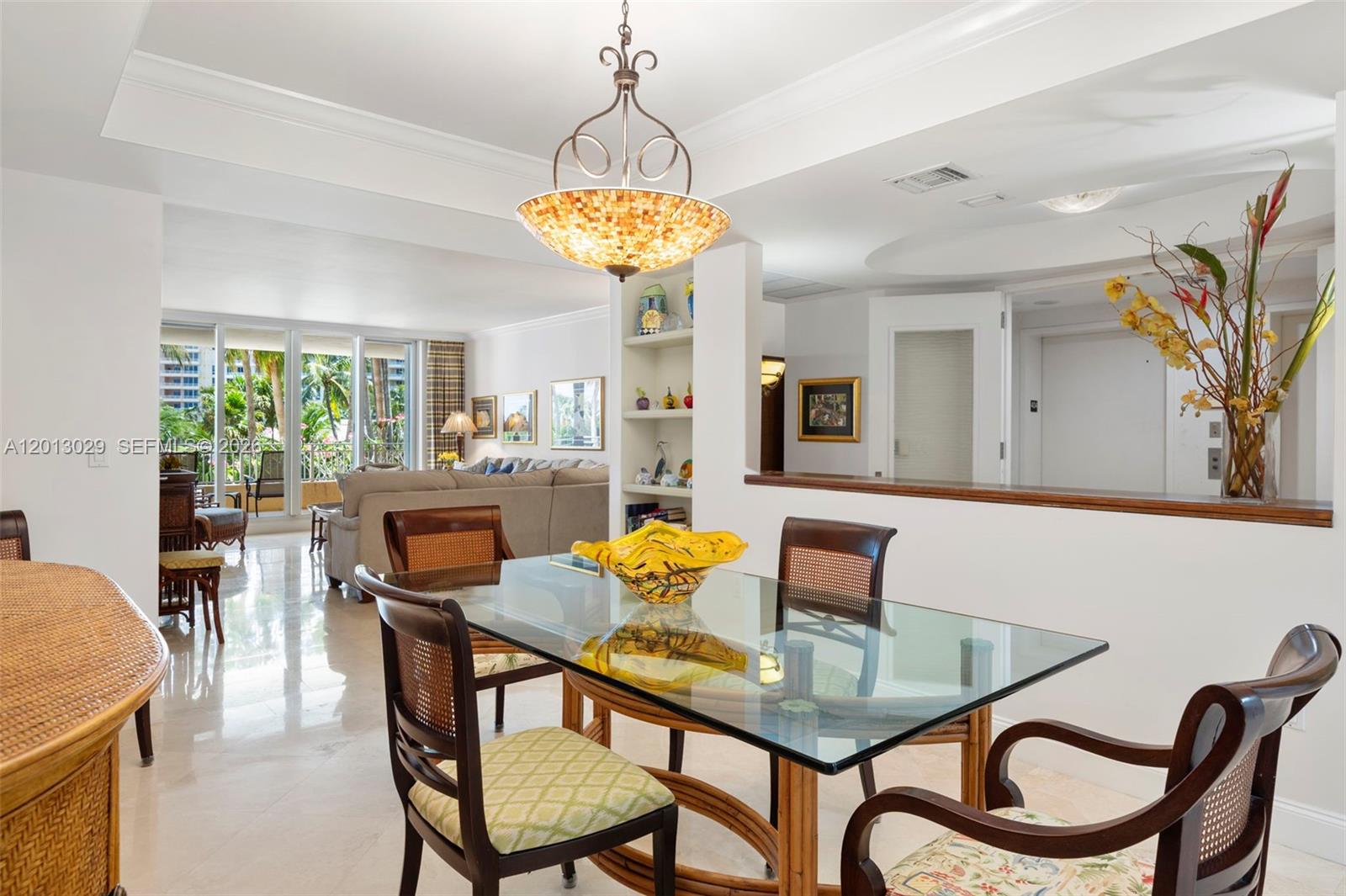 A dining area with a glass table and rattan chairs sits before a living room — 791 Crandon Blvd # 404, Key Biscayne FL 33149, KEY BISCAYNE, FL