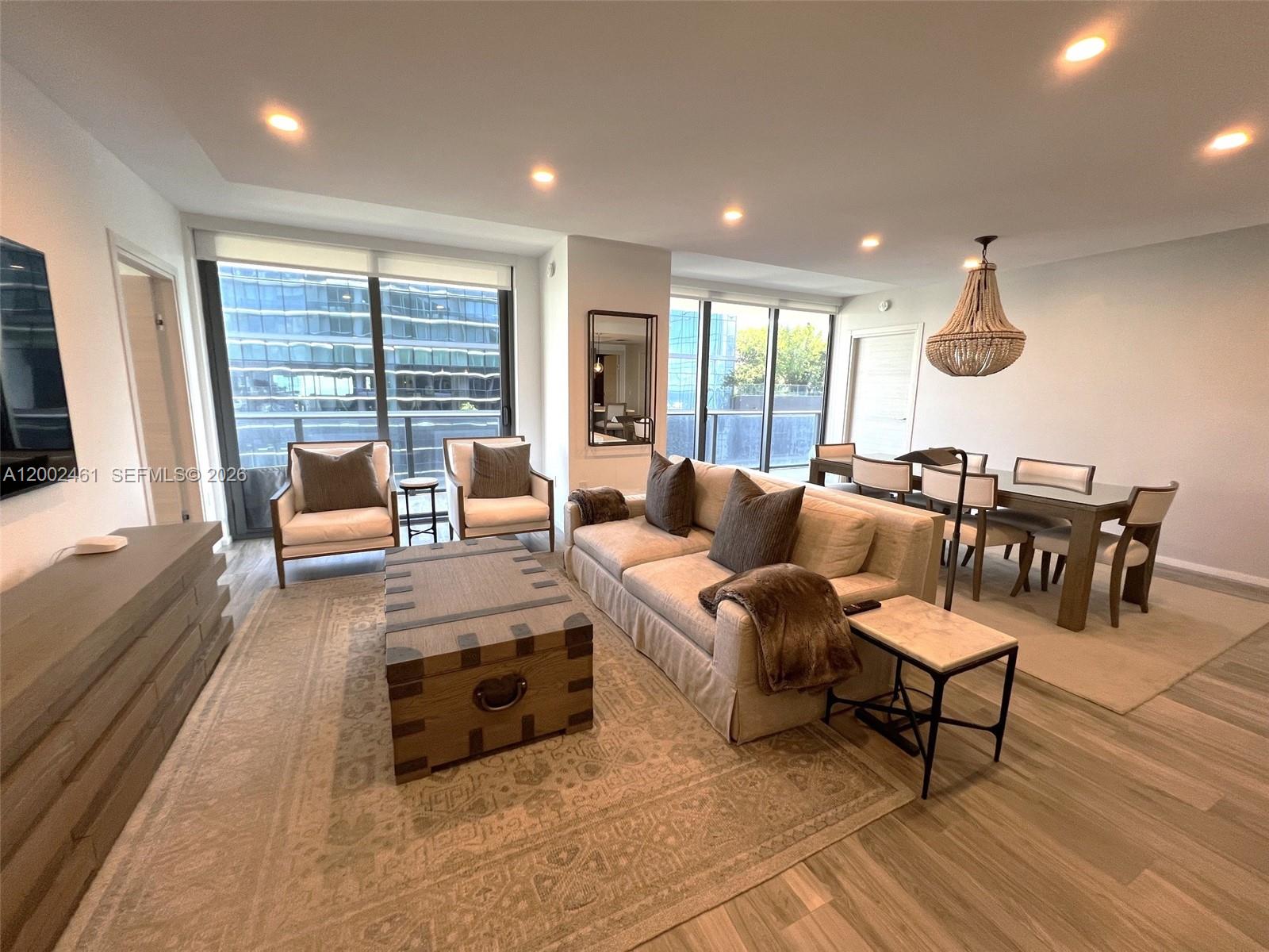 A modern living and dining area features a neutral sofa, trunk coffee table, and chandelier — 801 S Miami Ave # 4608, Miami FL 33130, MIAMI, FL