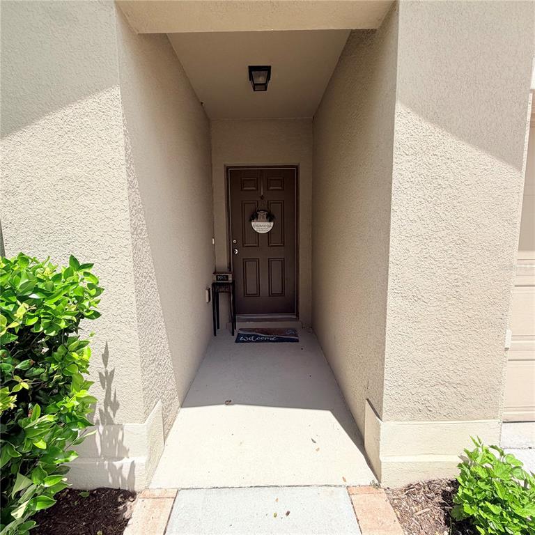 A recessed entryway features a brown front door, a small side table, and a welcome mat — 439 PINK CORAL LANE, NEW SMYRNA BEACH, FL