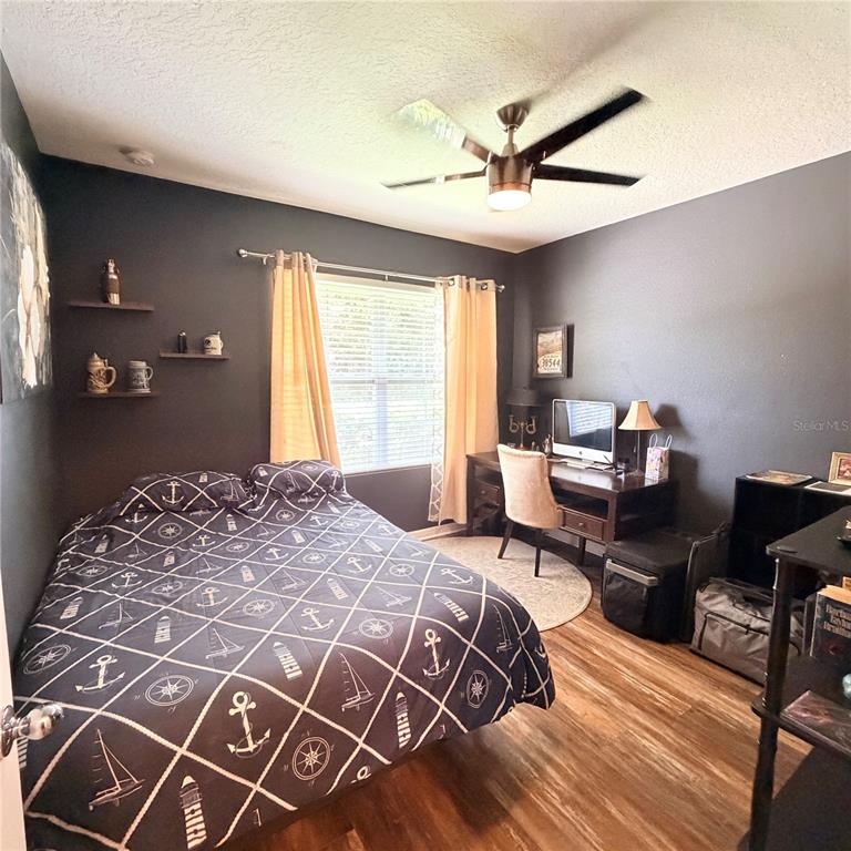 A bedroom with dark walls, a nautical-themed bedspread, a desk, and a ceiling fan — 439 PINK CORAL LANE, NEW SMYRNA BEACH, FL
