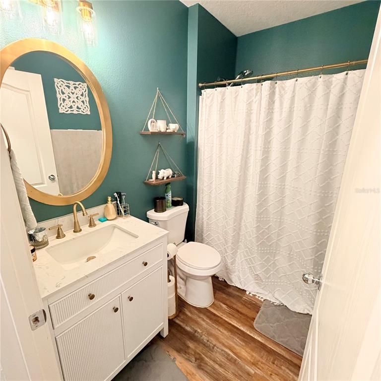 A bathroom features a white vanity, a round gold mirror, and teal-painted walls — 439 PINK CORAL LANE, NEW SMYRNA BEACH, FL