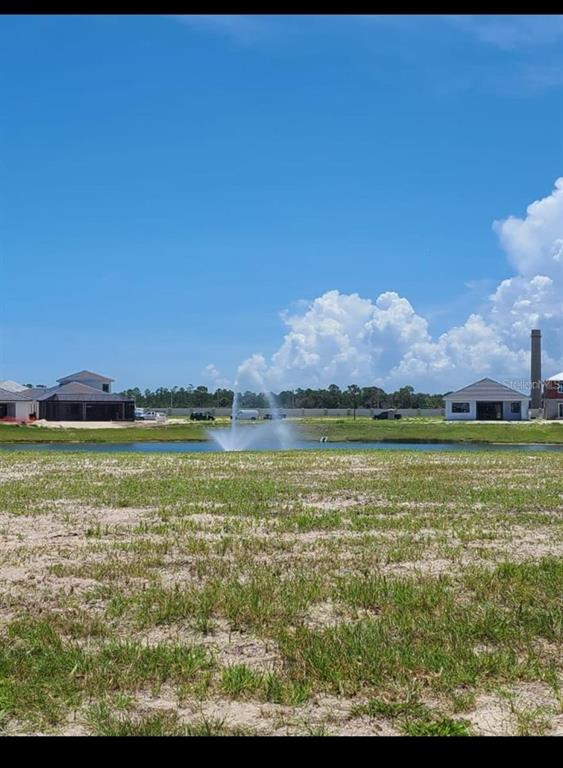 A vacant lot overlooks a pond with a fountain and nearby houses under construction — 21 DEL PALMA DRIVE, PALM COAST, FL