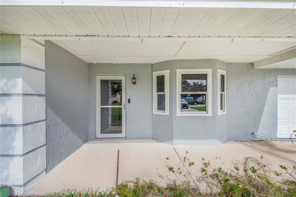 A covered concrete porch leads to a front door and a bay window — 632 REINDEER DRIVE, POINCIANA, FL