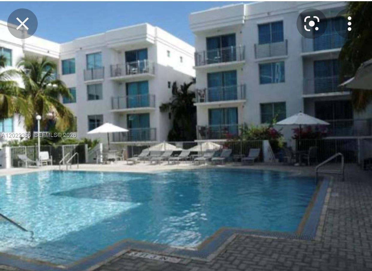 A swimming pool sits in front of a multi-story white apartment building with balconies — 110 Washington Ave # 1614, Miami Beach FL 33139, MIAMI BEACH, FL