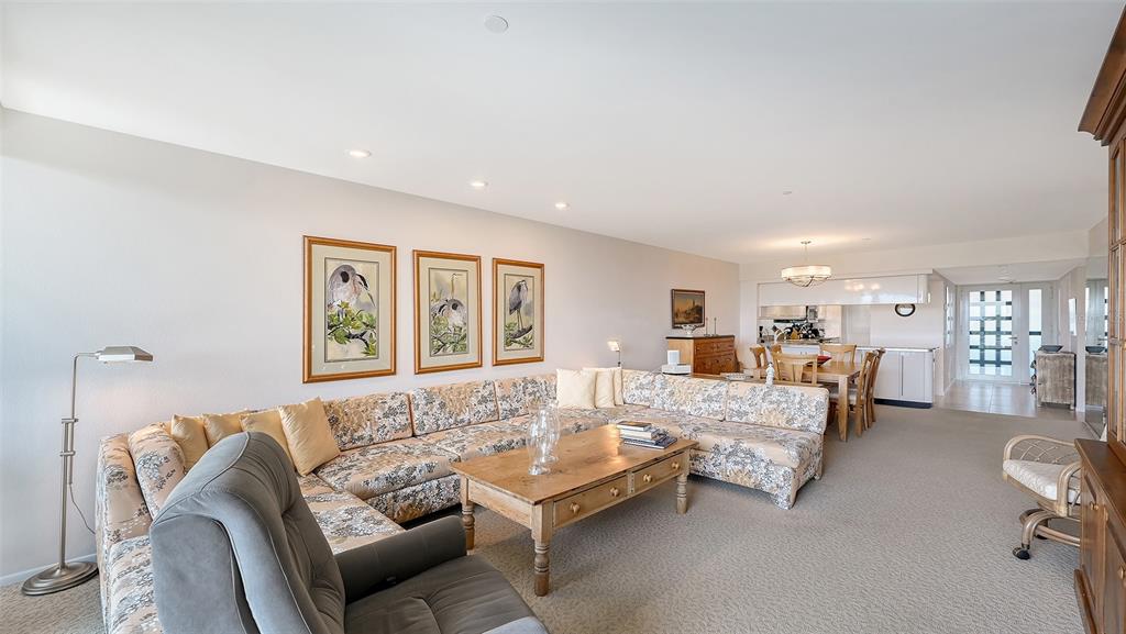 A living room features a large floral sectional sofa, a wooden coffee table, and dining area — 1085 GULF OF MEXICO DRIVE UNIT 404, LONGBOAT KEY, FL