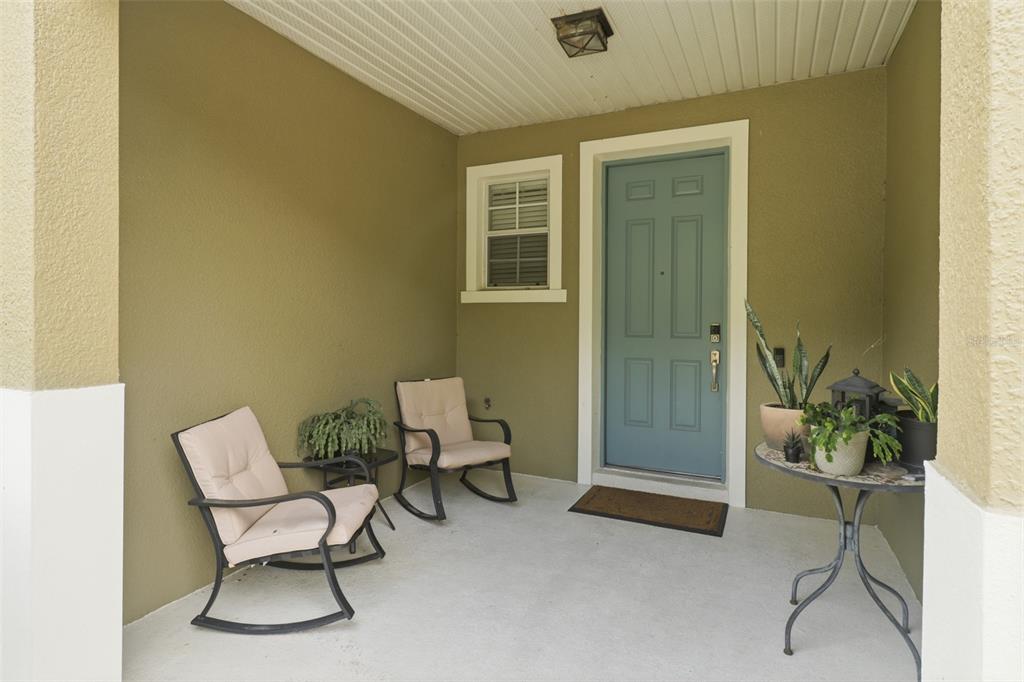 A covered front porch features two rocking chairs, a small table, and a blue door — 3845 GLIDING PLACE, SANFORD, FL