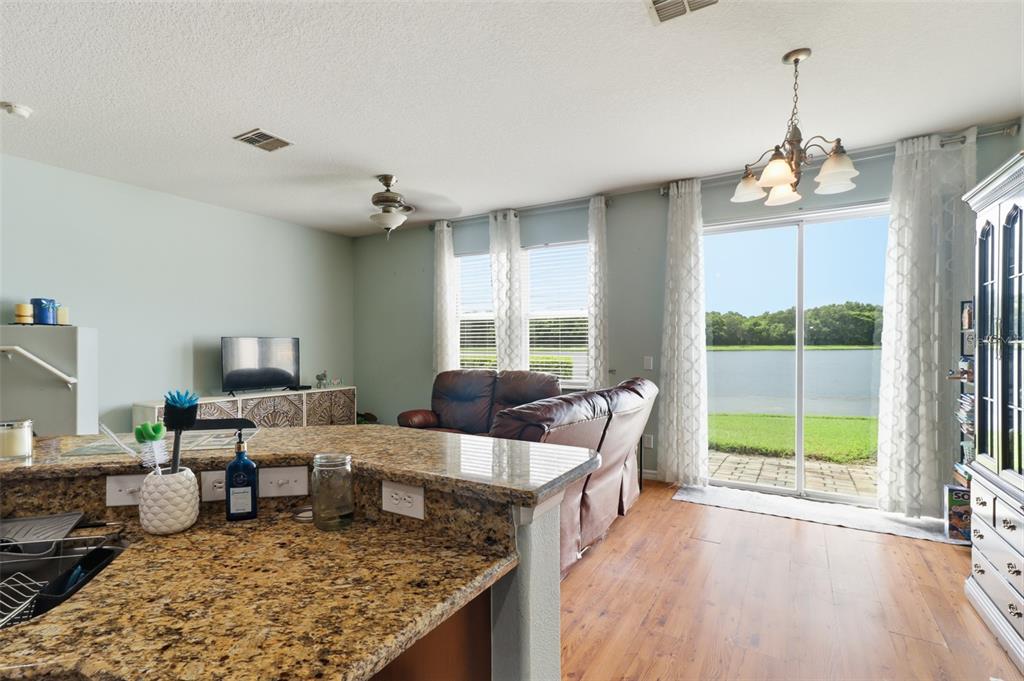 A living room with a granite kitchen island, brown leather sofa, and sliding glass patio doors — 3845 GLIDING PLACE, SANFORD, FL