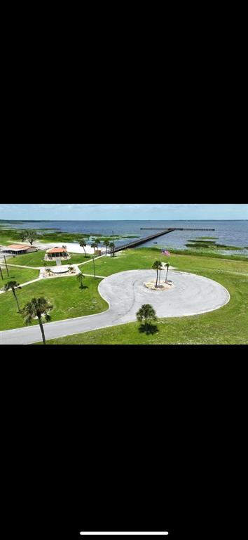 An aerial view shows a park with a circular driveway, palm trees, and a long pier — 313 CALENDULA DRIVE, INDIAN LAKE ESTATES, FL
