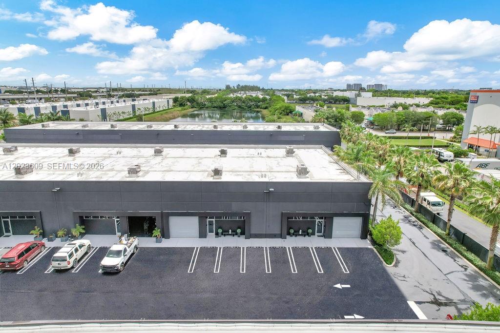 An aerial view shows a commercial building with a parking lot and a nearby pond — 6030 NW 102nd Ave # 211, Doral FL 33178, DORAL, FL