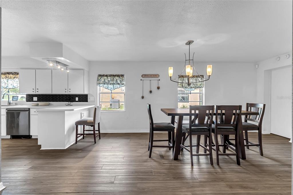 A dining area with a dark wood table and chairs sits adjacent to a white kitchen — 320 S SEMINOLE AVENUE, LAKE ALFRED, FL