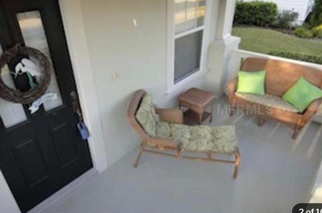 A covered front porch features a wicker chaise lounge, a small table, and a wicker loveseat — 848 RUNNER OAK STREET, CELEBRATION, FL
