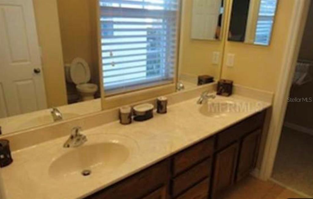 A bathroom features a double vanity with dark wood cabinets and a large mirror — 848 RUNNER OAK STREET, CELEBRATION, FL