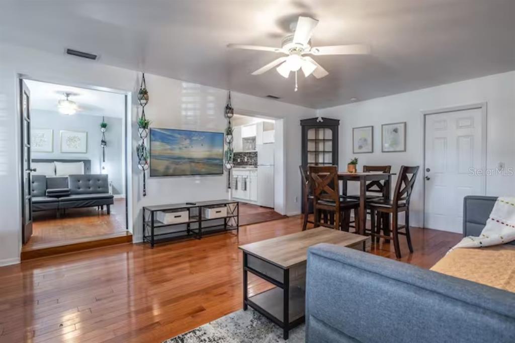 A living room with hardwood floors, a ceiling fan, a television, and an adjacent dining area — 3120 PEEL AVE UNIT 1, ORLANDO, FL
