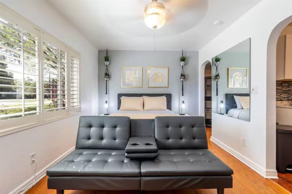 A bedroom features a black futon in the foreground, a bed, and a large wall mirror — 3120 PEEL AVE UNIT 1, ORLANDO, FL