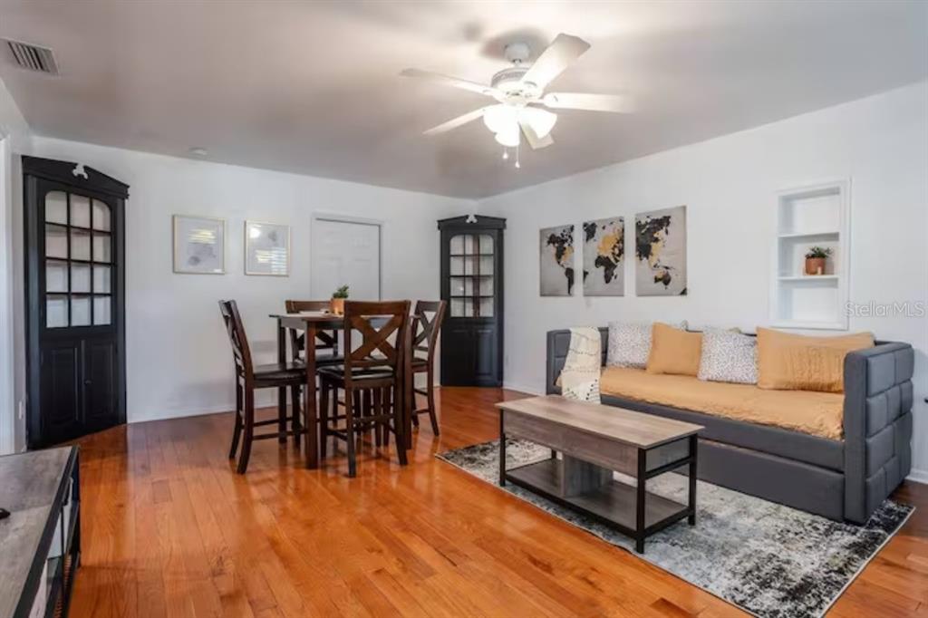 A living and dining room with hardwood floors, a grey sofa, and two black corner cabinets — 3120 PEEL AVE UNIT 1, ORLANDO, FL