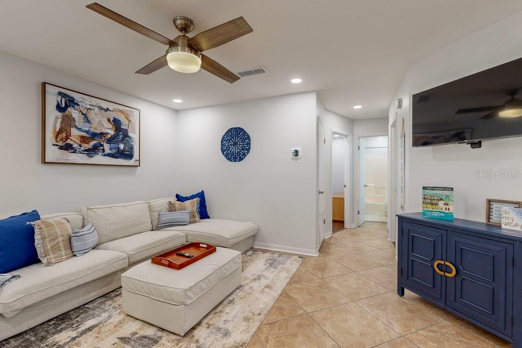 A living room features a beige sectional sofa, a ceiling fan, and a blue cabinet — 111 GULF WINDS COURT UNIT 111, DESTIN, FL