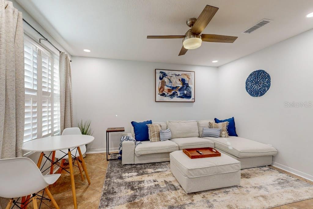 A living room features a beige sectional sofa, a matching ottoman, and a small dining table — 111 GULF WINDS COURT UNIT 111, DESTIN, FL