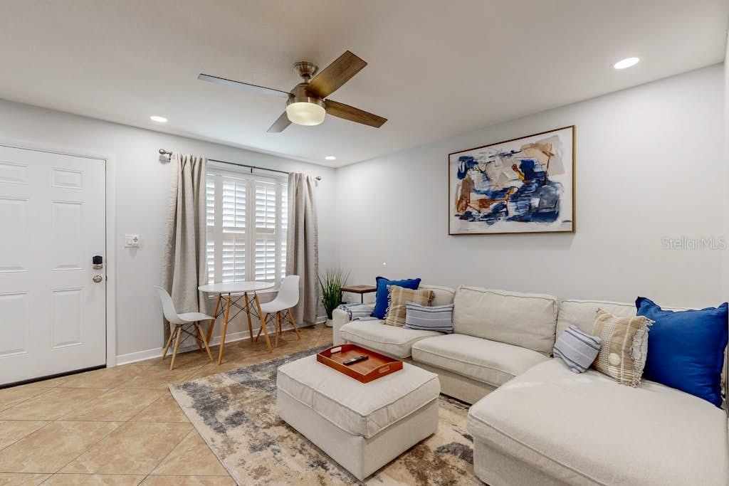 A living room features a beige sectional sofa, a matching ottoman, and a small dining area — 111 GULF WINDS COURT UNIT 111, DESTIN, FL