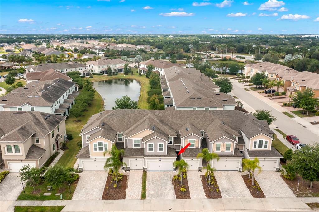 An aerial view shows a row of townhouses with attached garages and a central pond — 5018 SUNNYSIDE LANE, BRADENTON, FL
