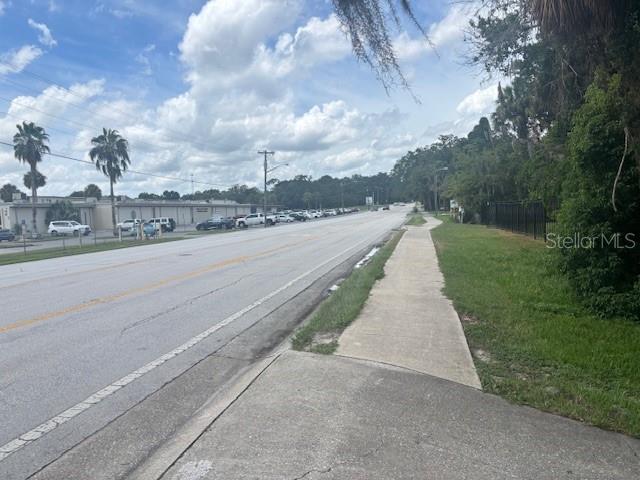 A view of a paved road with a sidewalk and palm trees under a cloudy sky — 1807 E FORT KING STREET, OCALA, FL