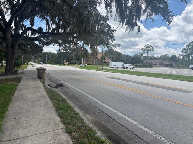 A sidewalk runs alongside a paved road with large trees and buildings in the background — 1807 E FORT KING STREET, OCALA, FL