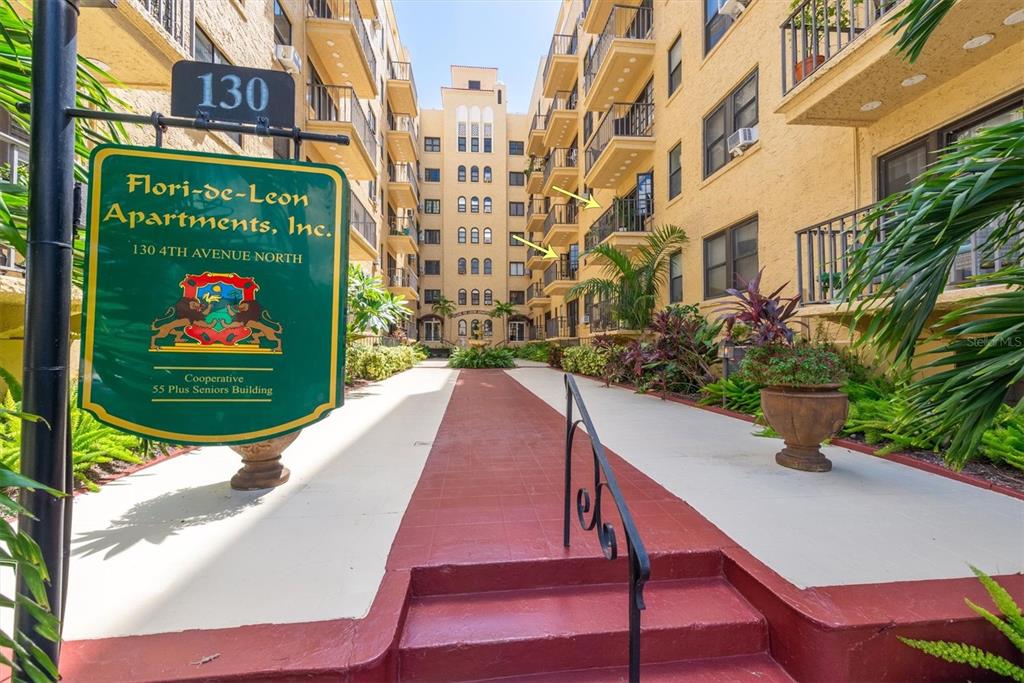 A courtyard view of a multi-story apartment building with a prominent entrance sign — 130 4TH AVENUE N UNIT 201, ST PETERSBURG, FL