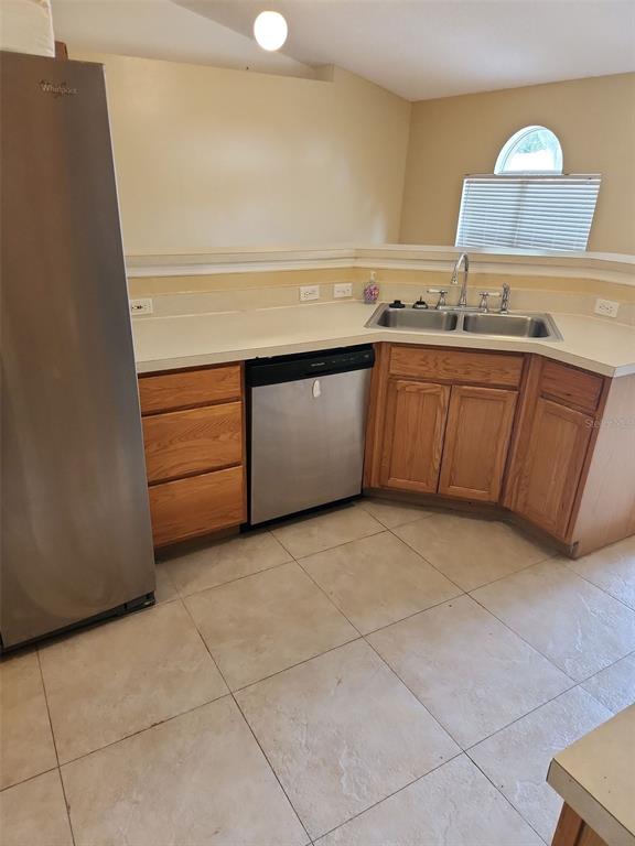 A kitchen features stainless steel appliances, oak cabinets, a double sink, and tiled flooring — 1411 S MARY STREET, EUSTIS, FL