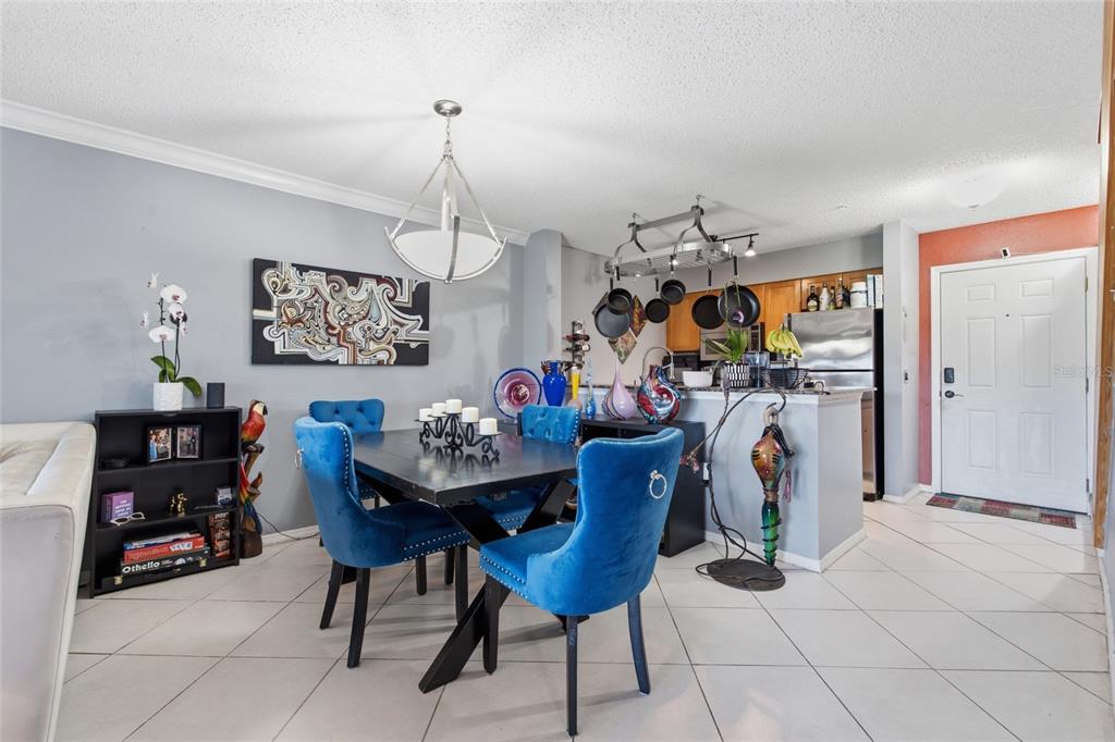 A dining area with blue velvet chairs, a dark table, and an open kitchen background — 2400 FEATHER SOUND DRIVE UNIT 313, CLEARWATER, FL